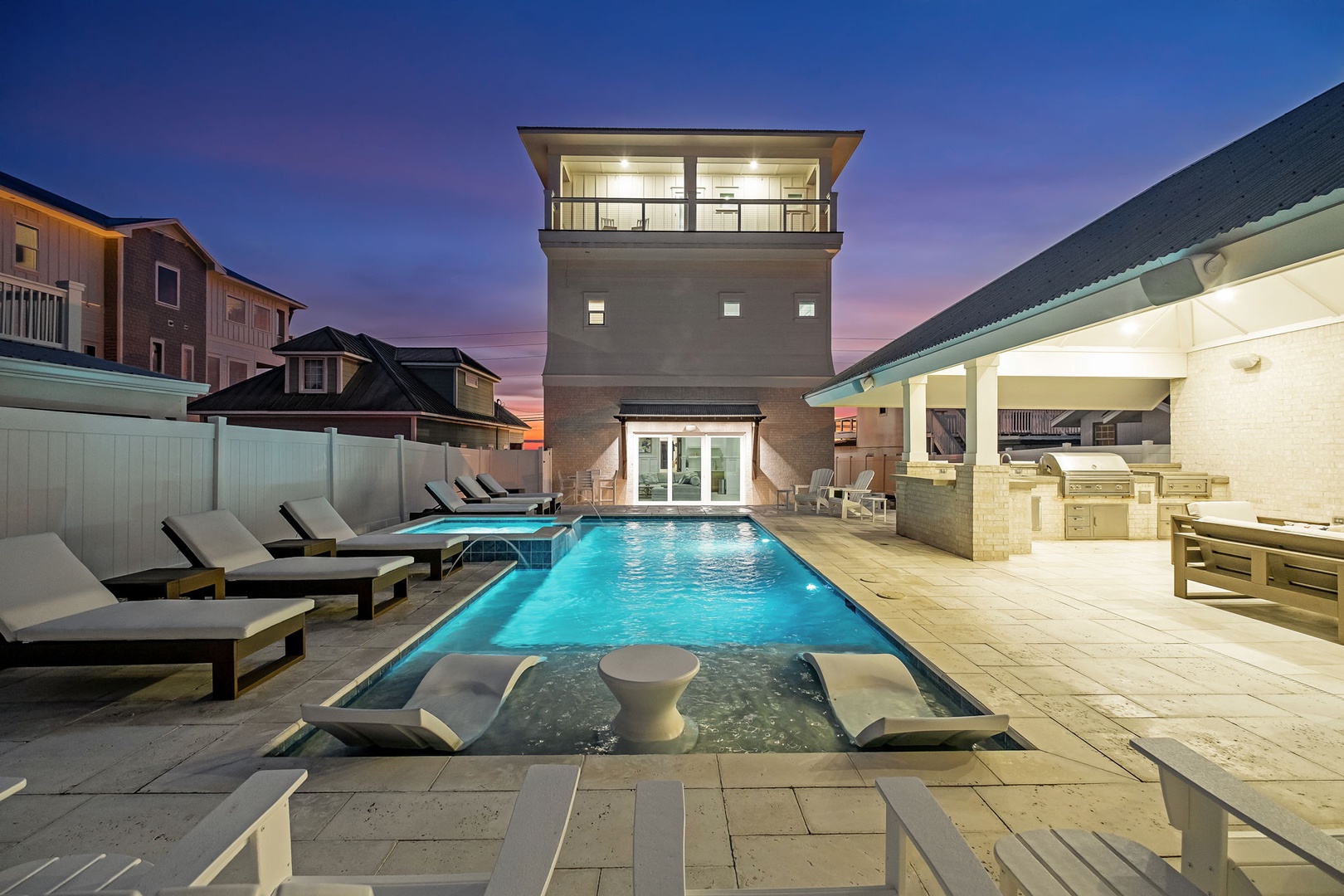 Modern vacation rental with illuminated pool area and outdoor entertainment space captures the beauty of twilight hours.