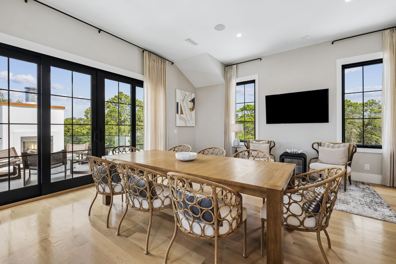 Gather around the handsome oak dining table and enjoy meals with lush garden views through soaring black-framed windows. Natural light fills the vaulted space, creating a warm, inviting atmosphere perfect for your vacation memories.