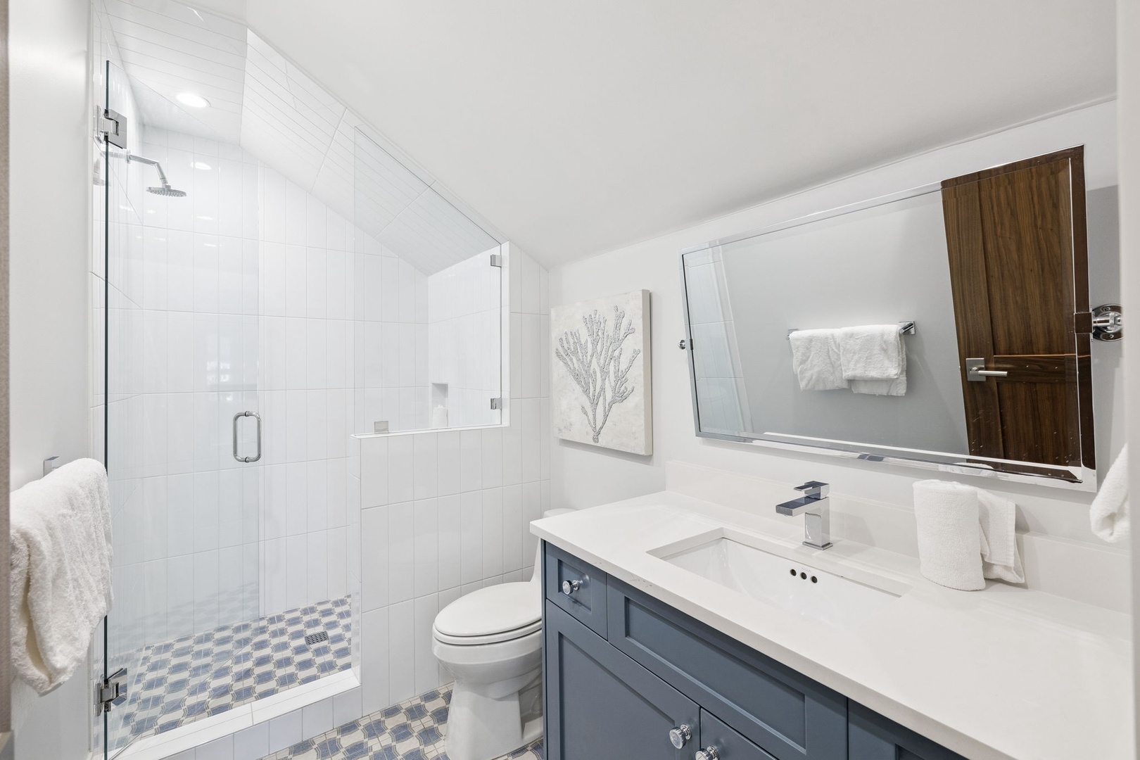 Step into your spa-like bathroom featuring a walk-in glass shower, modern vanity, and crisp white tiles that create a serene retreat.