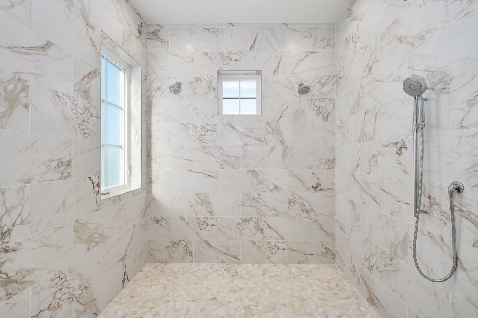 Step into your spa-like marble shower sanctuary with dual rainfall heads and natural light streaming through frosted windows.