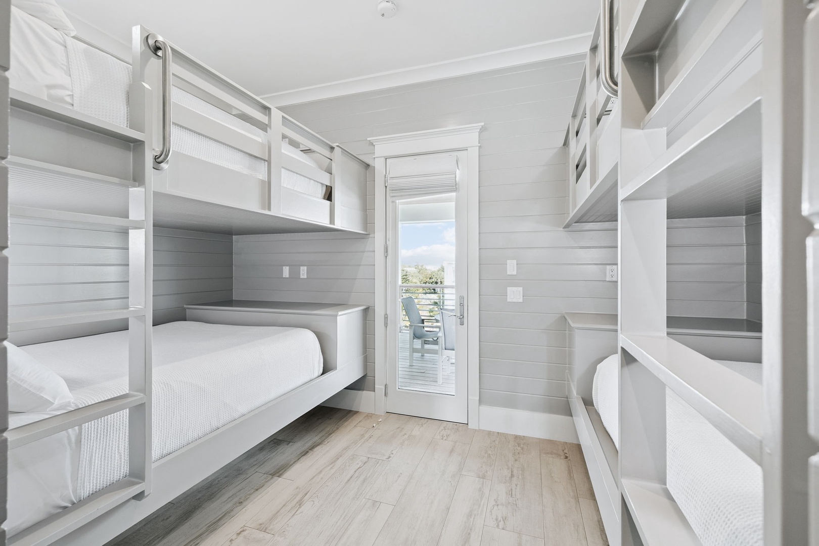 Your family will love this bright bunk room with four cozy beds and charming shiplap walls, perfect for creating lasting memories together.