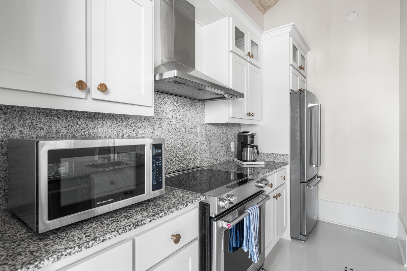 Your fully-equipped kitchen features gleaming granite counters, stainless steel appliances, and crisp white cabinetry—perfect for preparing meals during your stay.