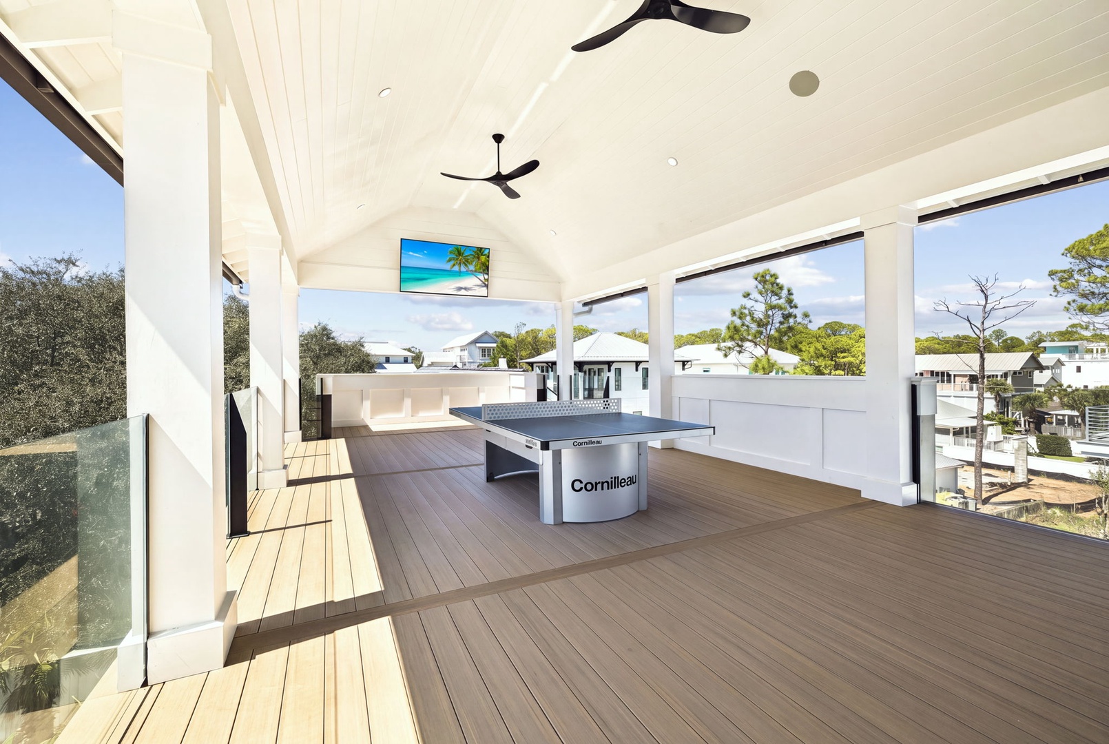 Imagine yourself here, playing table tennis under vaulted ceilings with ceiling fans keeping you cool. The covered deck opens to peaceful neighborhood views, perfect for year-round fun.