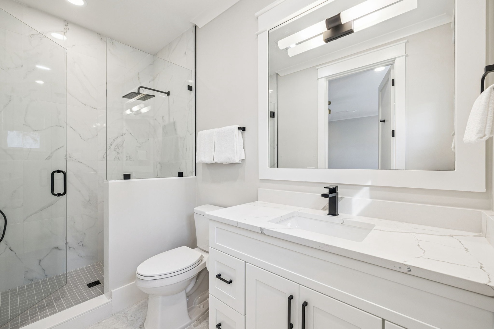 Step into your pristine marble bathroom with a spacious walk-in shower and elegant white vanity, where luxury meets comfort.