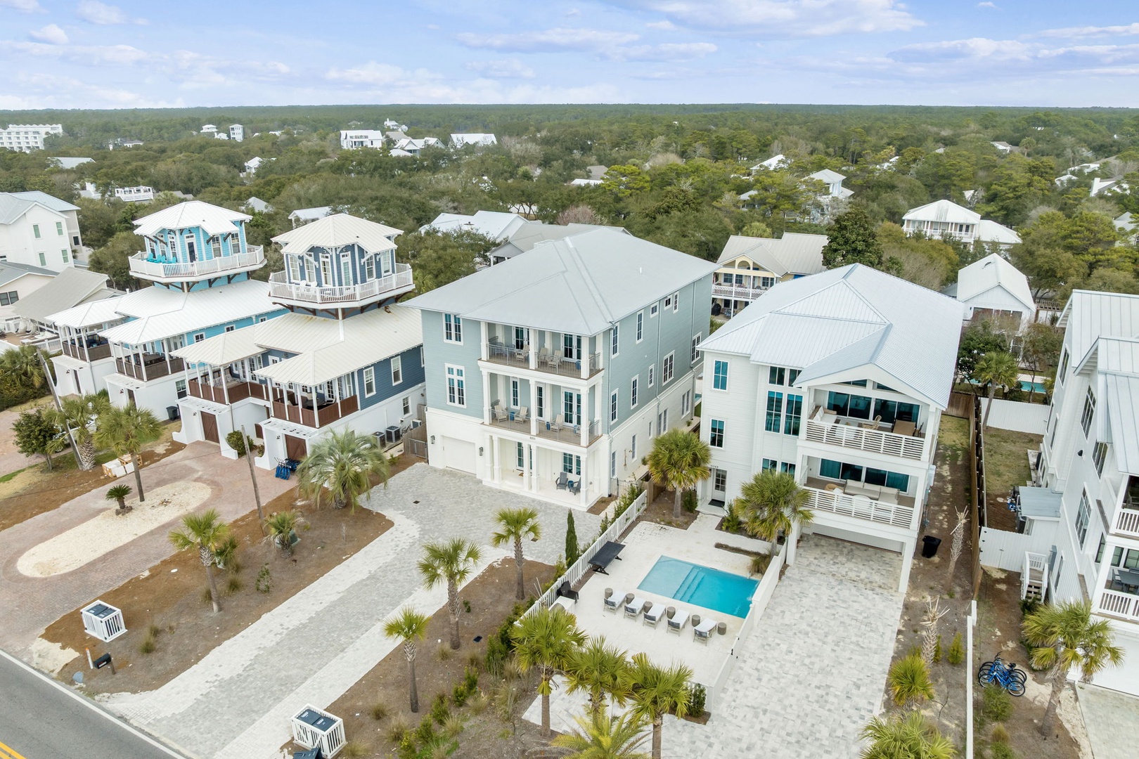 Aerial view of coastal vacation rentals in a tree-lined residential community with beach-style architecture and modern amenities.