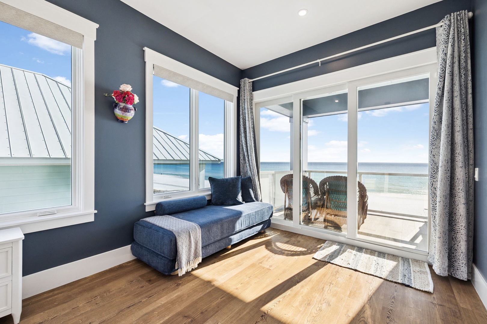 Relax on your private chaise with sweeping ocean views through floor-to-ceiling windows in this coastal blue retreat.