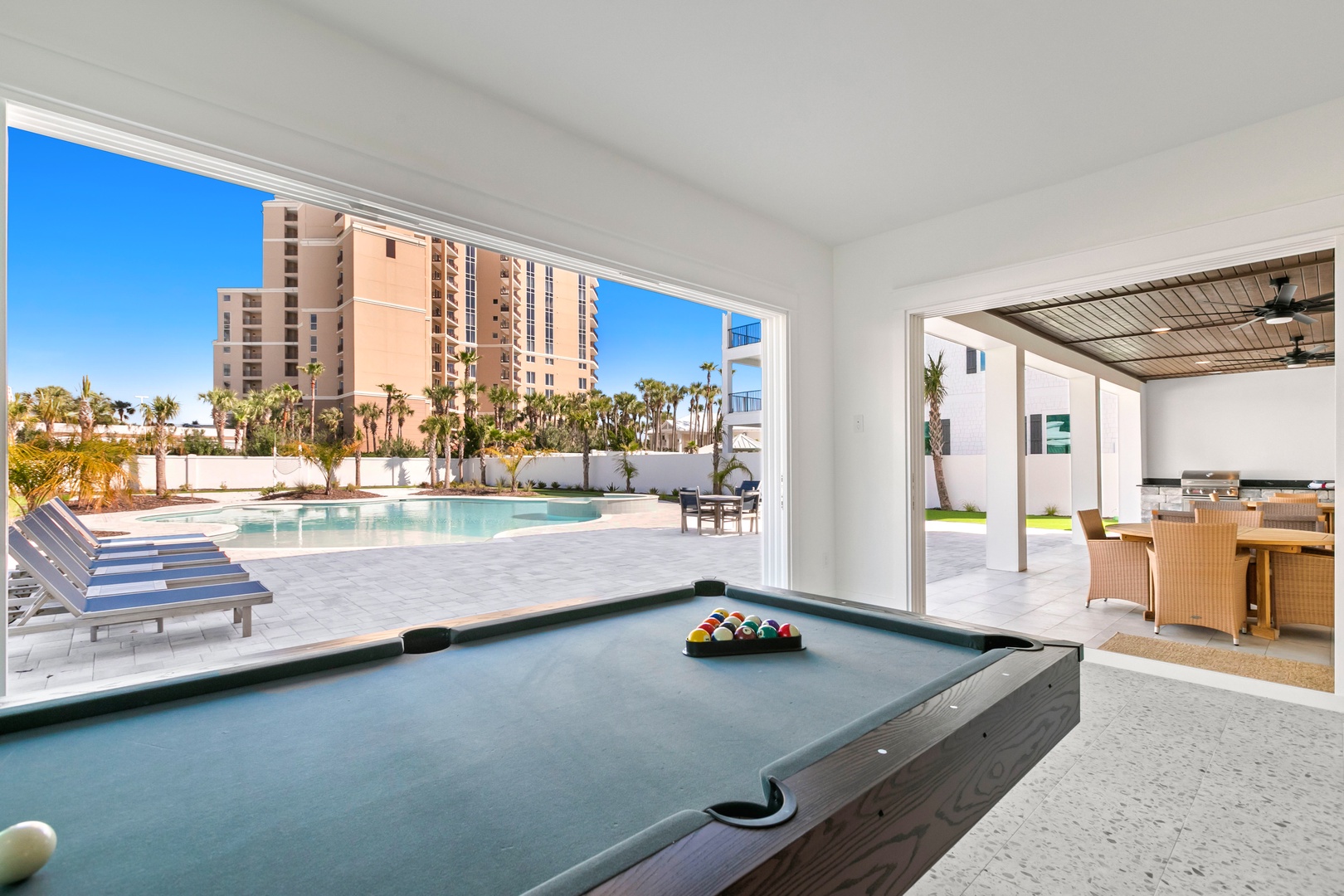 Challenge friends to a game of billiards as your gaze drifts to the sparkling pool and palm trees framed by floor-to-ceiling windows—your perfect blend of play and relaxation.