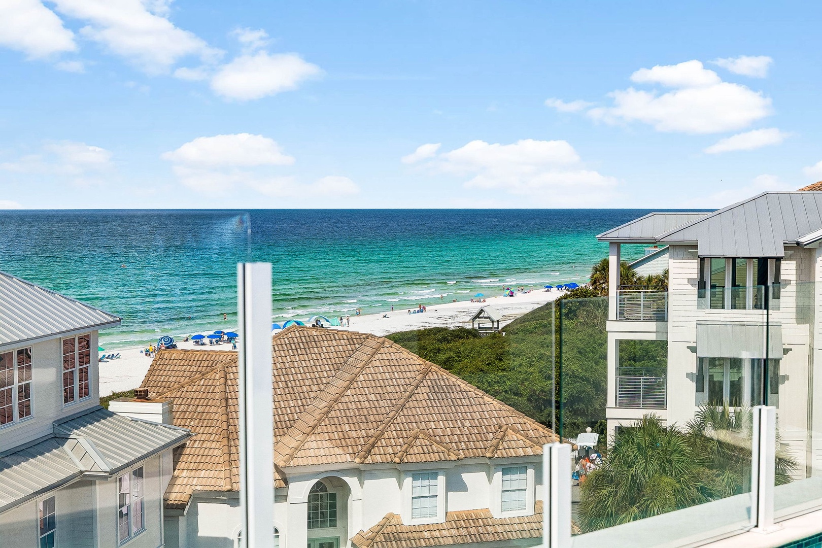 Coastal neighborhood near pristine turquoise waters and white sand beach, with beachfront homes featuring classic tile roofs and stunning Gulf views.