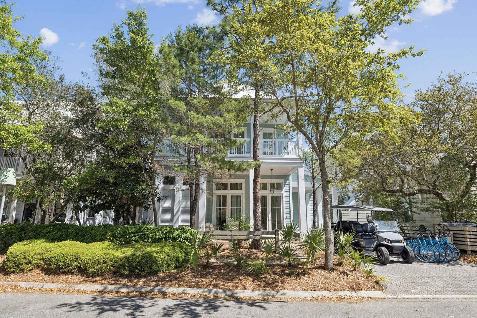 Elegant two-story home nestled among mature trees with landscaped gardens and convenient bike storage for exploring the area.