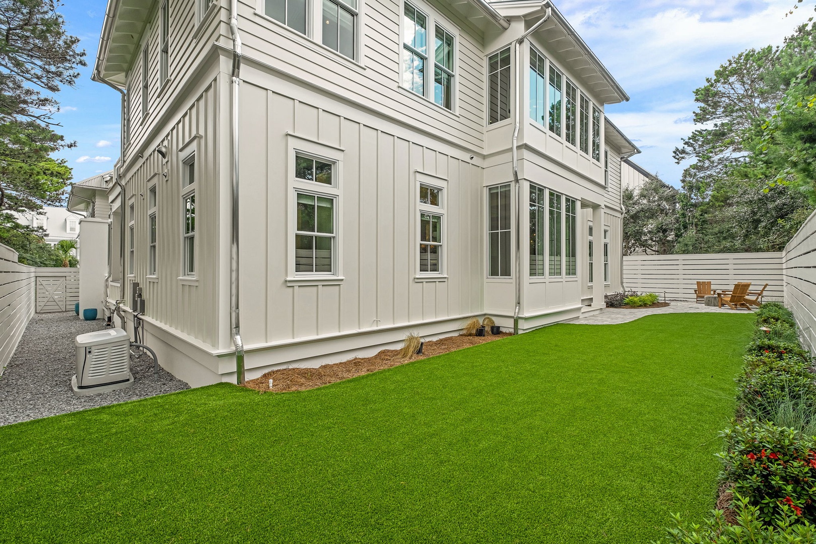 This modern two-story home features elegant board and batten siding, multiple windows, and a spacious private backyard with lush green lawn—ideal for relaxing or outdoor gatherings.