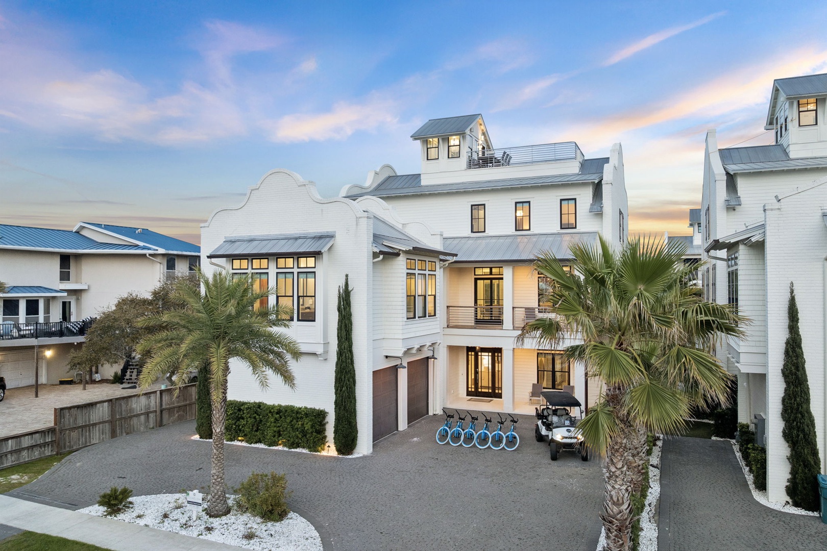 Modern coastal villa with elegant white architecture and palm-lined entrance in an exclusive beachside community.