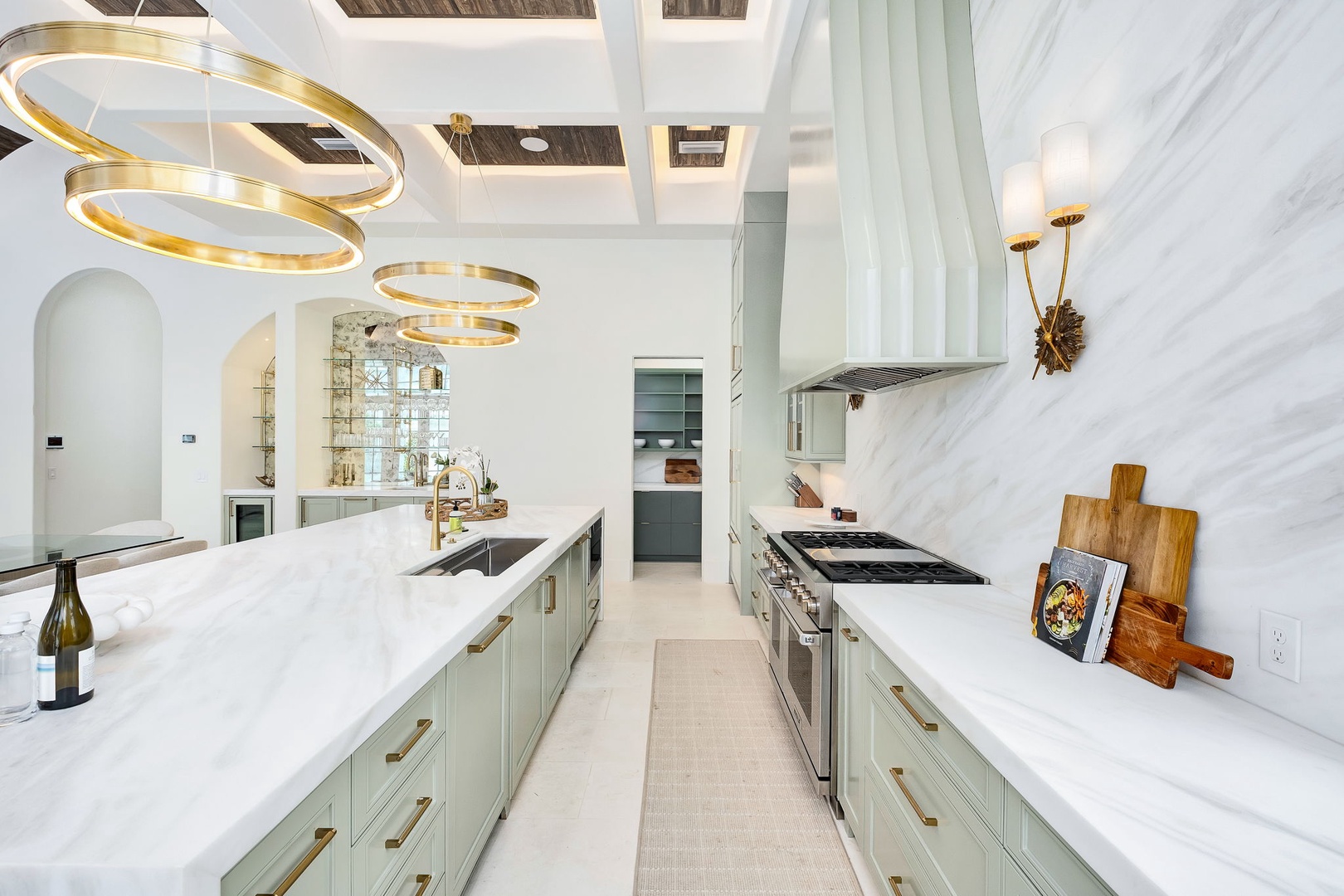Step into your gourmet kitchen where sleek marble countertops, soft mint cabinetry, and gleaming brass fixtures create an elegant yet inviting space for preparing meals and gathering with loved ones.