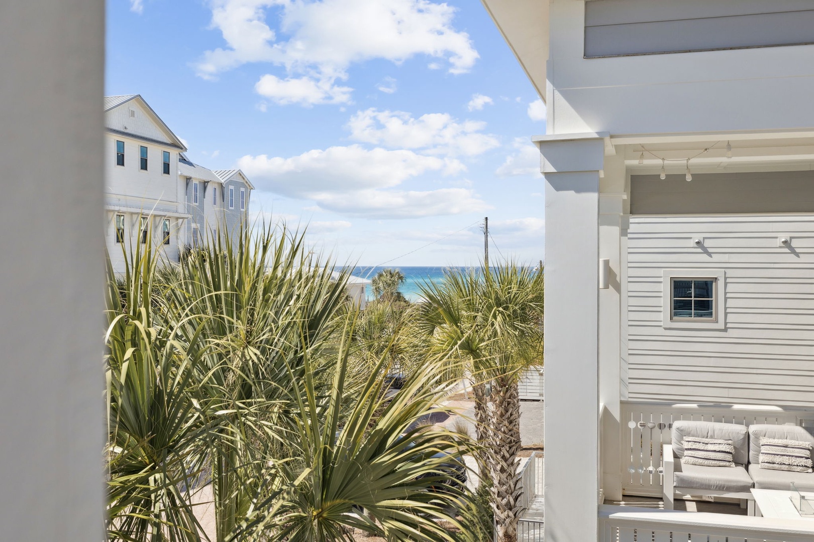 Stunning ocean views peek through tropical palms from your private balcony, where coastal breezes and comfortable seating create the perfect spot to unwind.