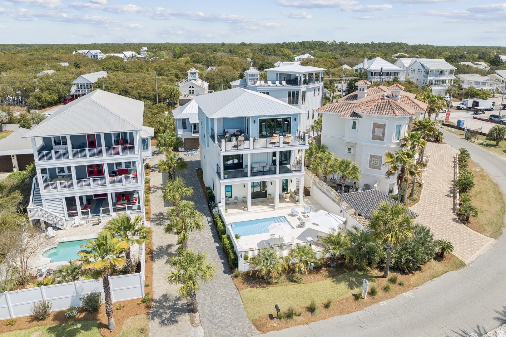 Stunning aerial view of luxurious vacation homes in a coastal community, featuring pristine swimming pools and tropical landscaping.