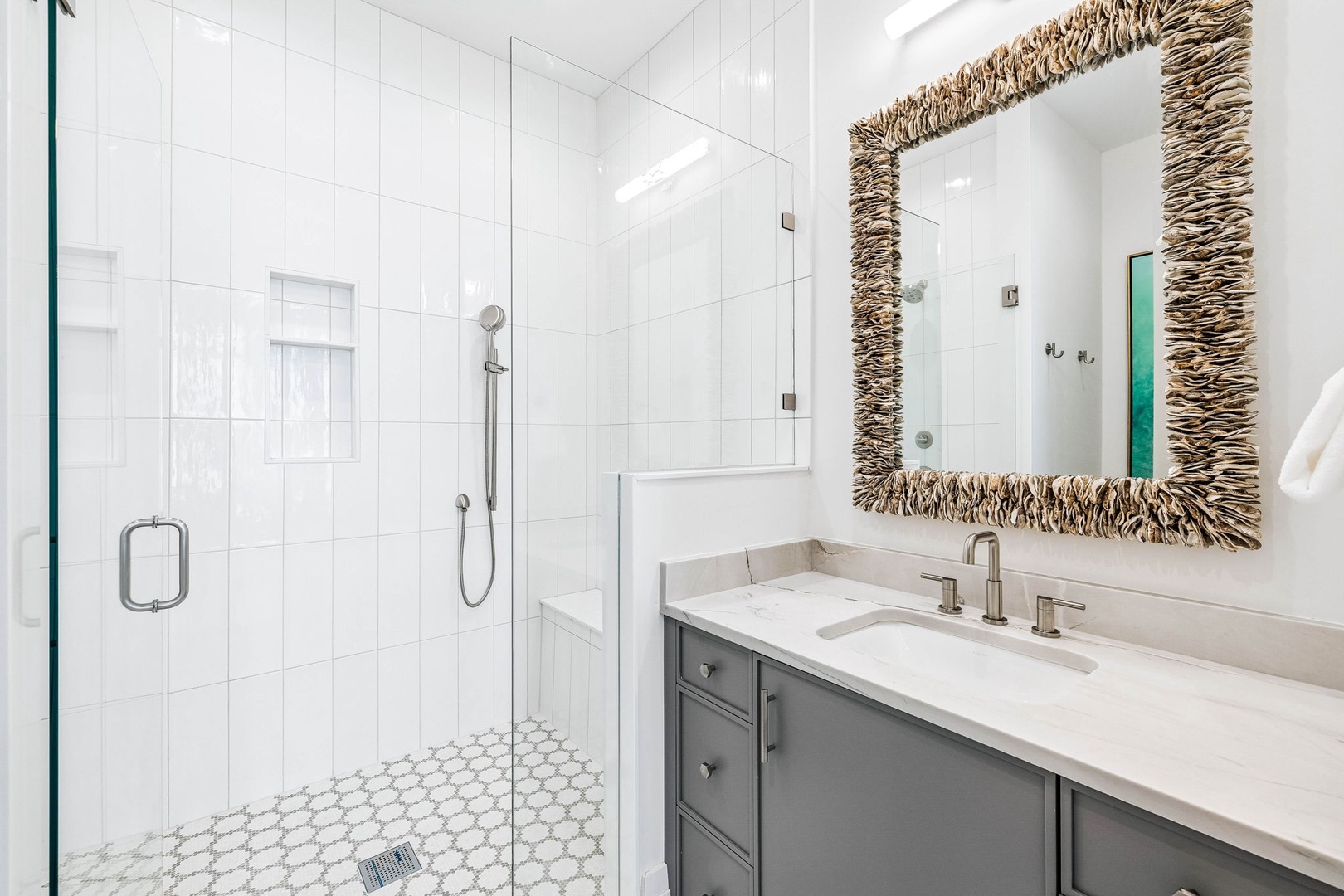 Step into your beautifully appointed bathroom, where a spacious walk-in shower and elegant marble vanity await. The coastal-inspired mirror adds a touch of natural charm to your refreshing retreat.