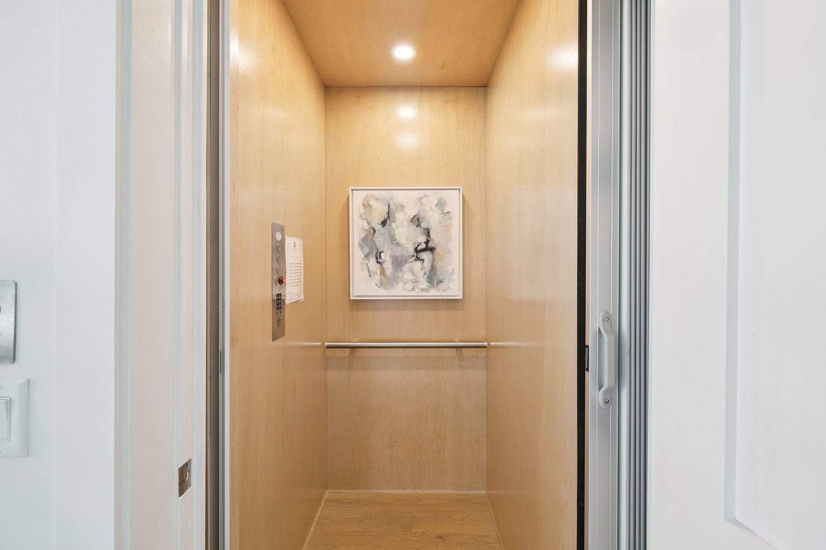 Step into your private elevator with warm wood paneling and elegant artwork, ensuring effortless access to your retreat.