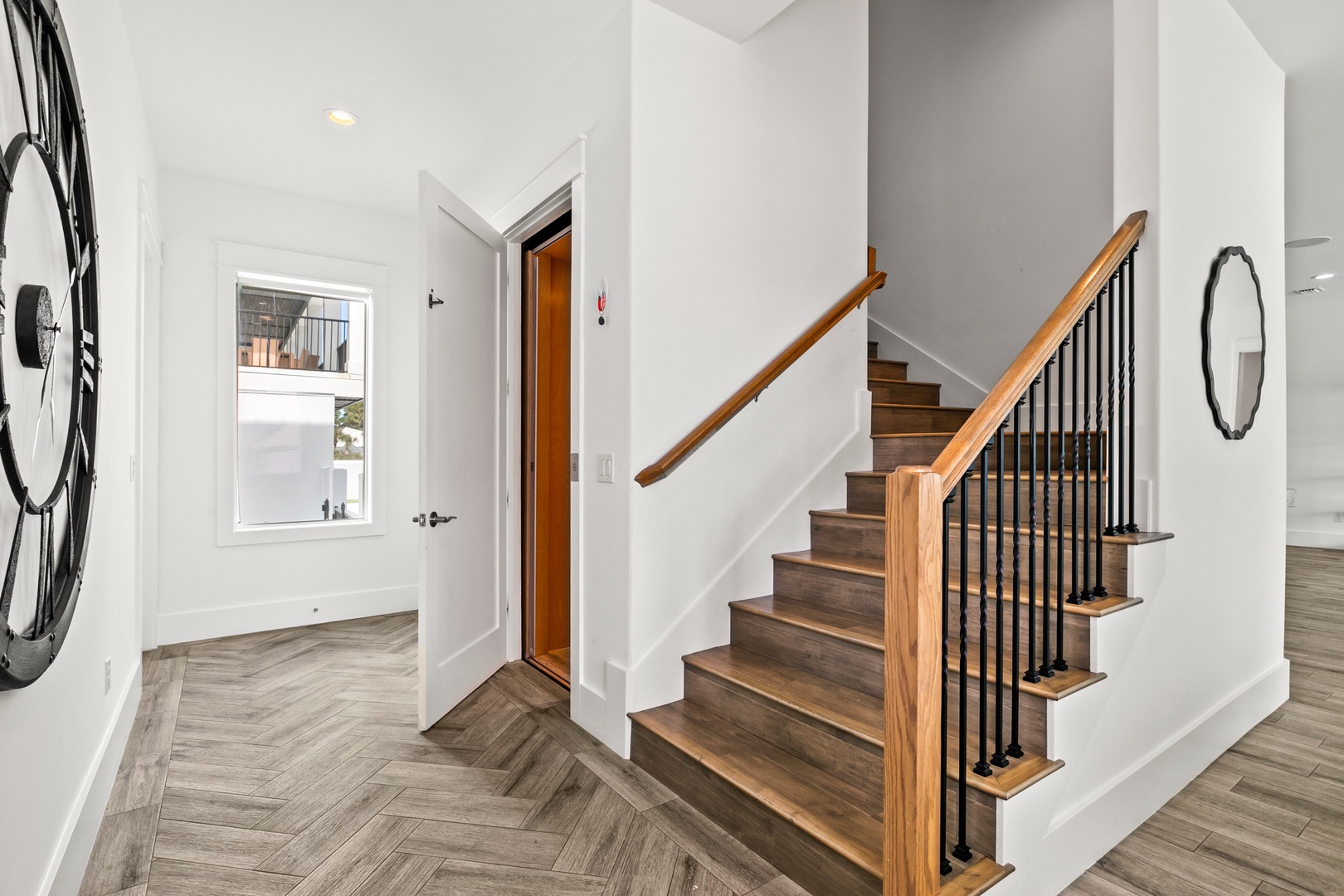 Step into a bright, modern entryway with sleek wood floors and an elegant staircase that sets the tone for your stay.