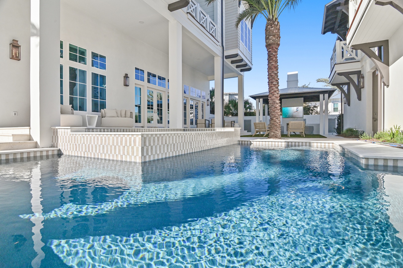 Sparkling turquoise waters invite you to unwind at the private pool, framed by elegant tilework and tropical palms. Your serene escape awaits beneath endless blue skies.