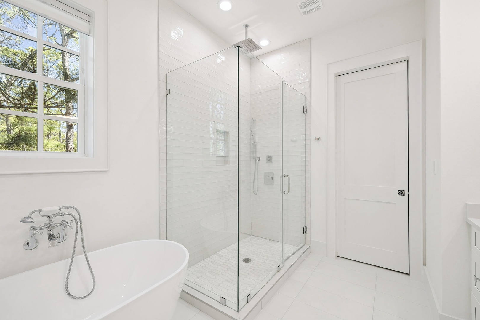 Indulge in your private spa-like bathroom with rainfall shower and soaking tub surrounded by pristine marble and natural light.