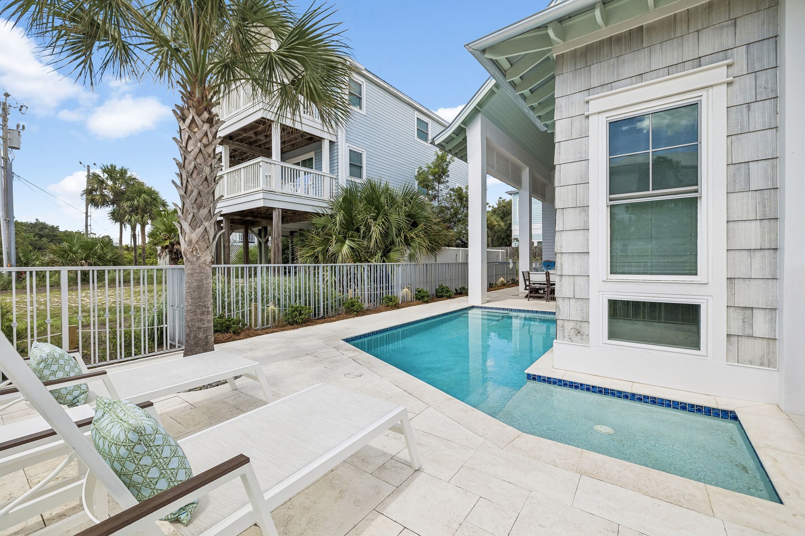 This tropical oasis in the surrounding neighborhood features a private pool nestled among swaying palms, with nearby elevated beach homes visible in the background.