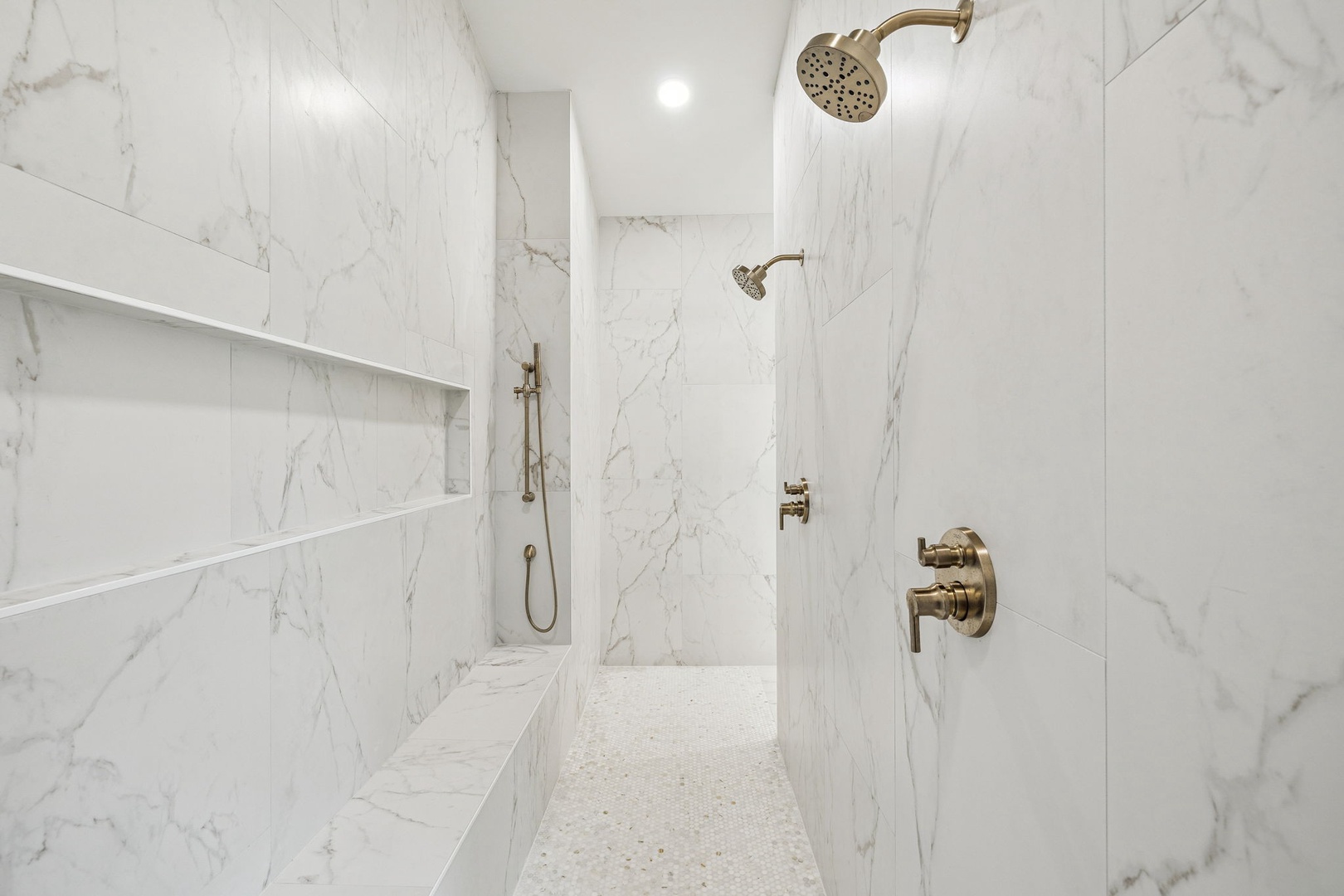 Step into your luxurious marble shower with dual rainfall heads and elegant gold fixtures for the ultimate spa experience.