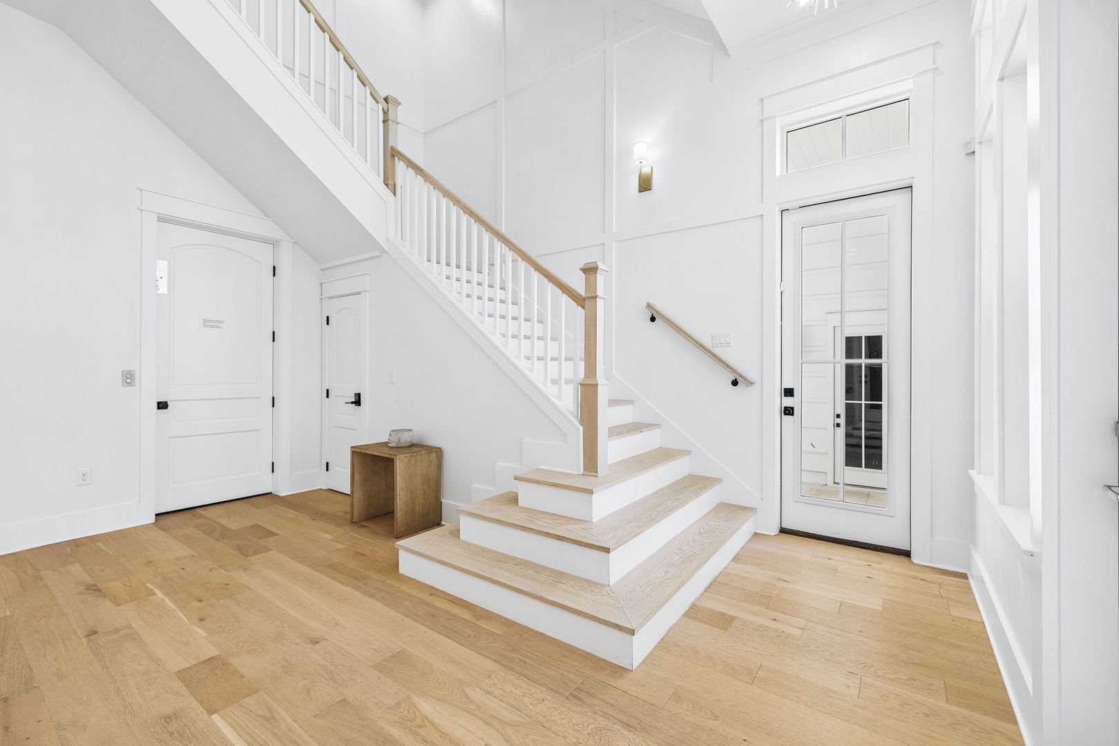 Step into a bright and airy entryway with soaring ceilings and warm hardwood floors, where natural light spills across the elegant staircase and inviting spaces waiting beyond.