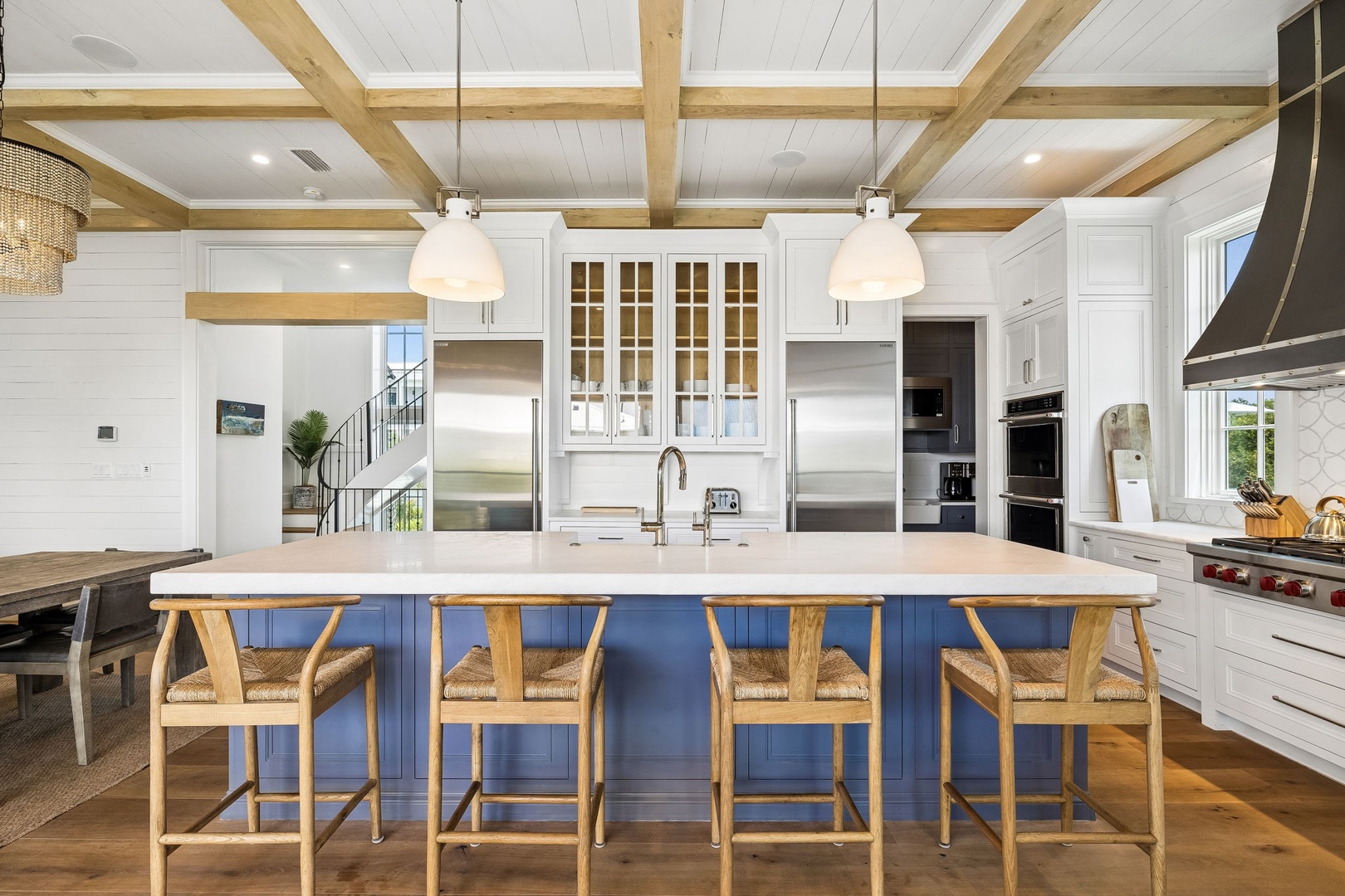 Picture yourself cooking in this stunning open kitchen with soaring wood-beam ceilings, spacious marble island, and top-tier stainless appliances—your culinary haven awaits.