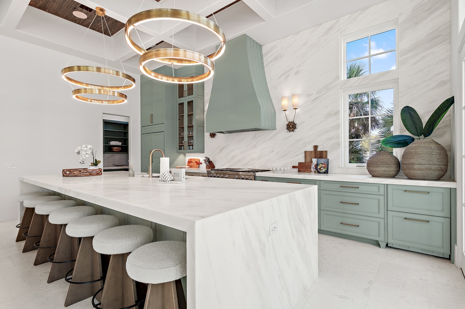 Your gourmet kitchen features soaring ceilings, elegant marble countertops, and soothing sage cabinetry—perfect for preparing meals while palm trees sway outside your windows.