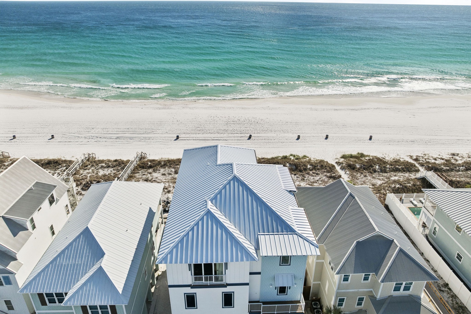 Beachfront community featuring coastal homes with direct beach access and pristine turquoise waters stretching to the horizon.