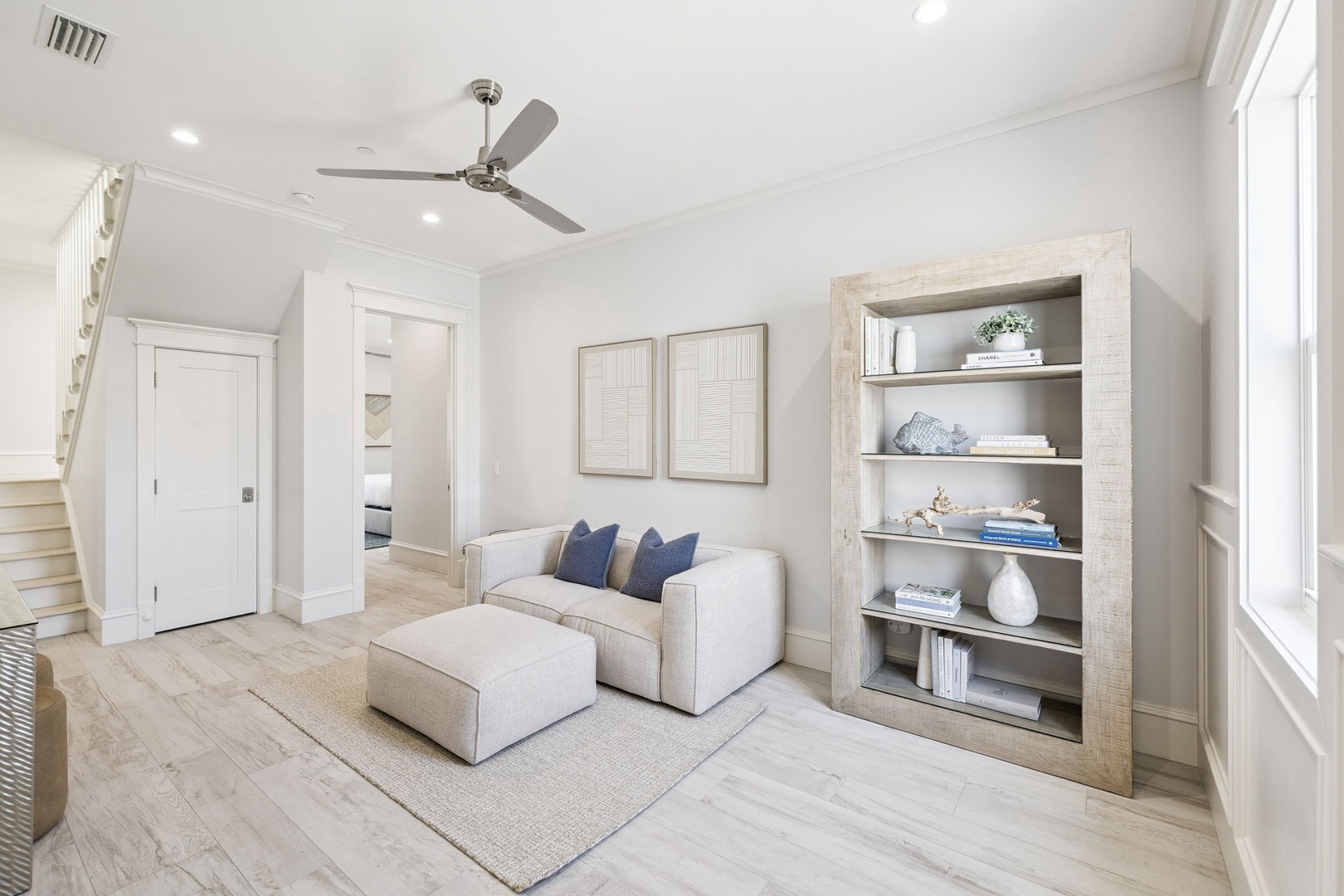 Sink into the plush sectional and feel the coastal breeze from the ceiling fan above. This bright living space invites relaxation with built-in shelving for your books.