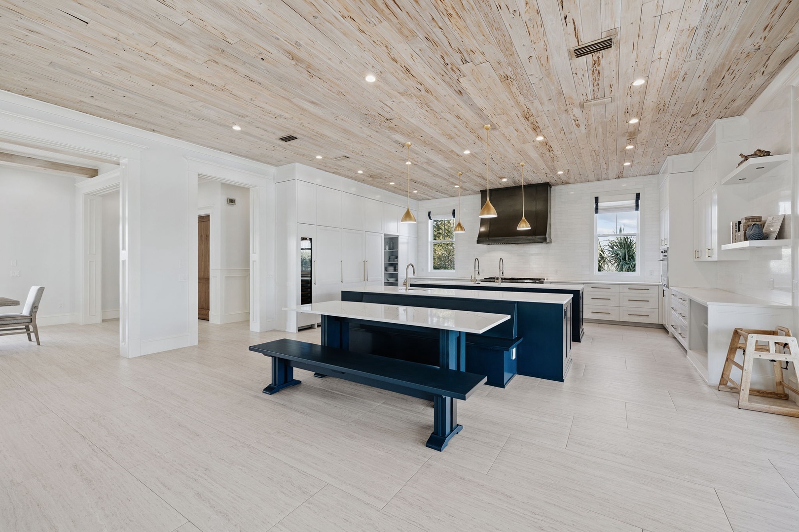 Stunning wood-plank ceiling creates warmth above your sleek gourmet kitchen with dual islands and premium appliances for memorable meal preparation.
