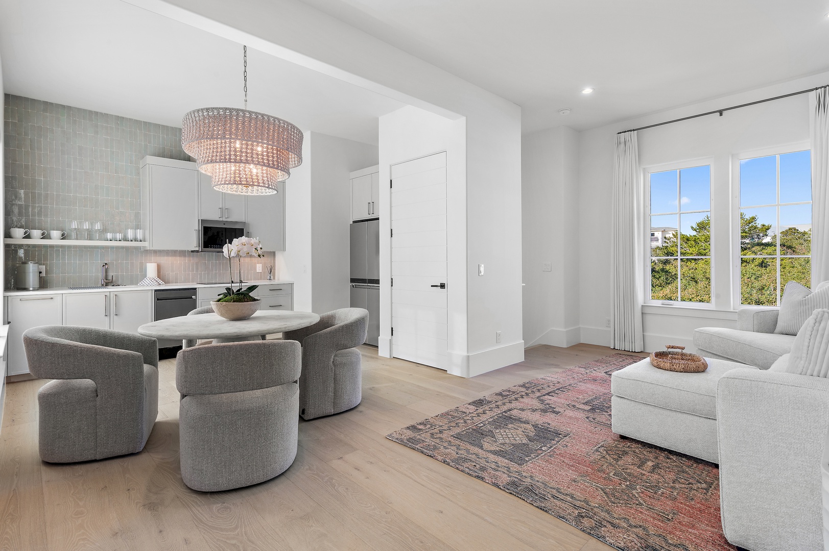 Bright, open living space with a fully equipped kitchen, elegant dining area, and plush seating where you can unwind and enjoy leafy views through expansive windows.