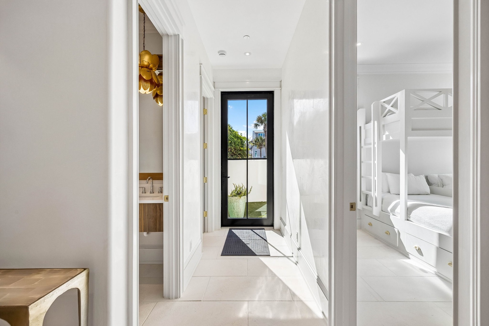 Step into a bright, airy hallway filled with natural light and coastal views. The crisp white interiors and thoughtful layout connect you to welcoming bedrooms and a charming bunk room perfect for family stays.