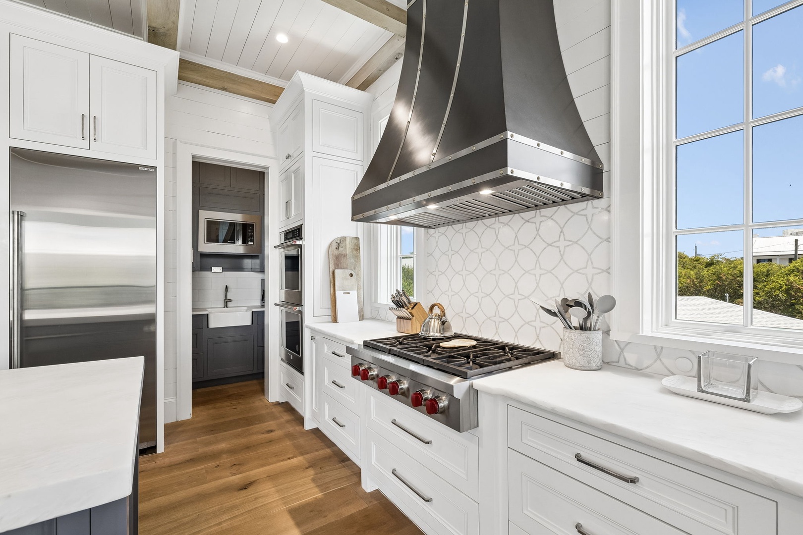 Your gourmet kitchen features professional-grade appliances, a statement range hood, and elegant white cabinetry—perfect for preparing memorable vacation meals with views of the surrounding greenery.