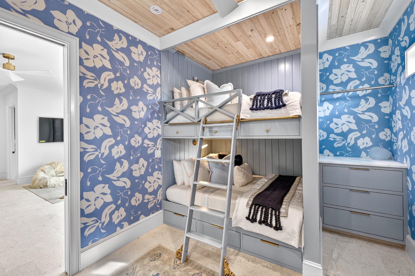 Picture your little ones settling into these charming custom bunk beds, surrounded by cheerful coastal-inspired wallpaper and warm wood ceilings that make bedtime feel like an adventure.