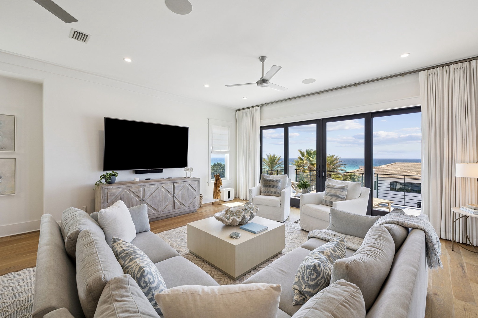 Sink into plush seating while enjoying stunning ocean views through floor-to-ceiling windows in this bright, modern living space designed for ultimate relaxation.