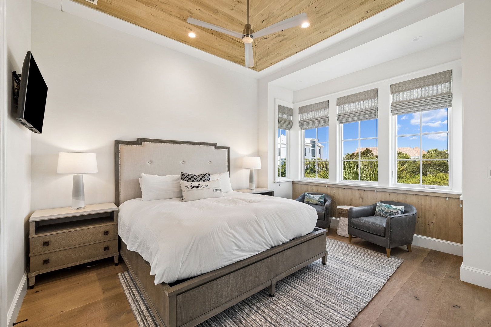 Sink into this plush king bed beneath vaulted wood ceilings. Sunlight streams through oversized windows revealing lush greenery while you relax in your cozy reading nook.