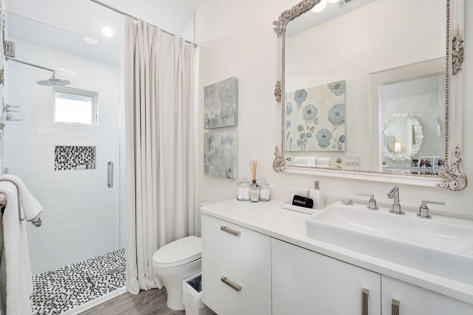 Freshen up in your elegant bathroom, where crisp white tones meet artistic touches and a spa-like shower awaits your morning routine.