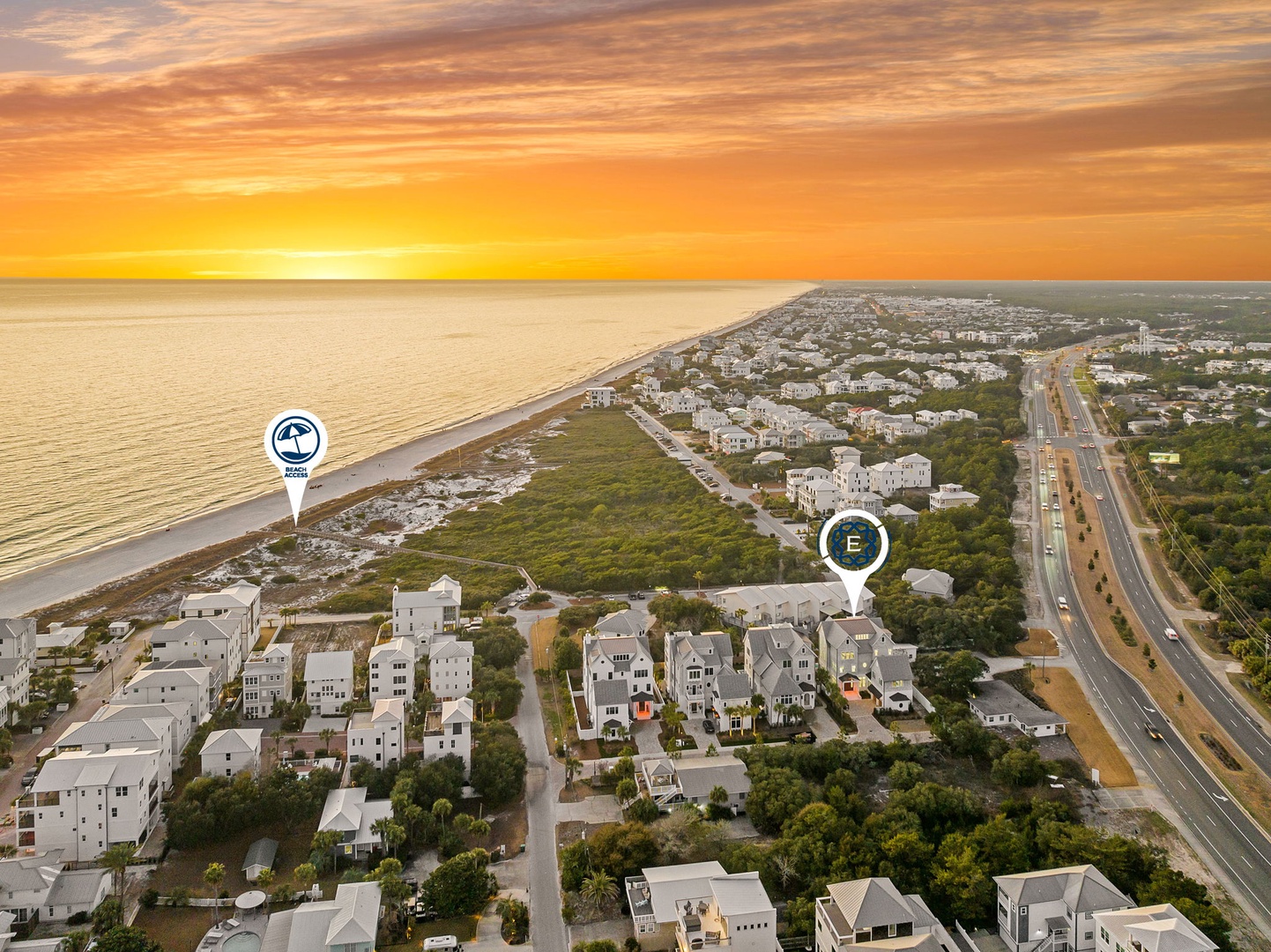 Aerial view of beachfront residential community during golden hour sunset, showing coastal properties and nearby highway access.