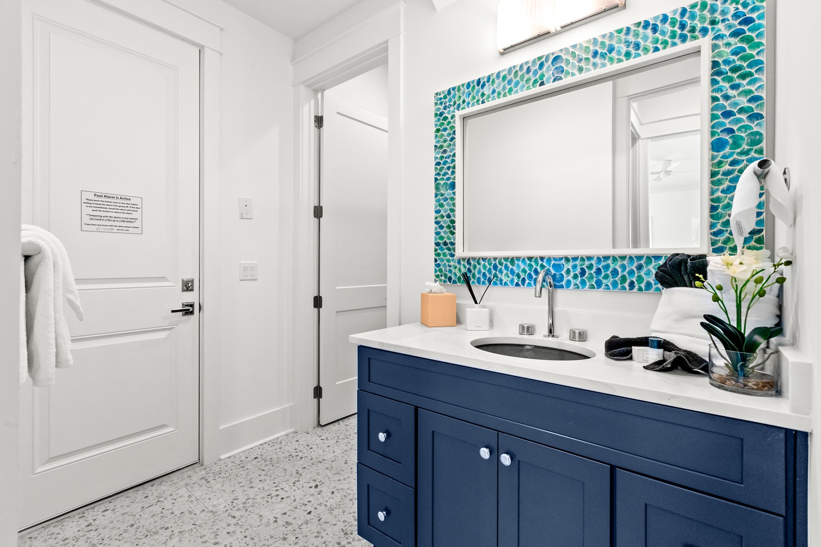 Freshen up in your stylish coastal-inspired bathroom, where ocean-blue mosaic tiles frame the mirror and set a calming, beachy mood for your mornings.