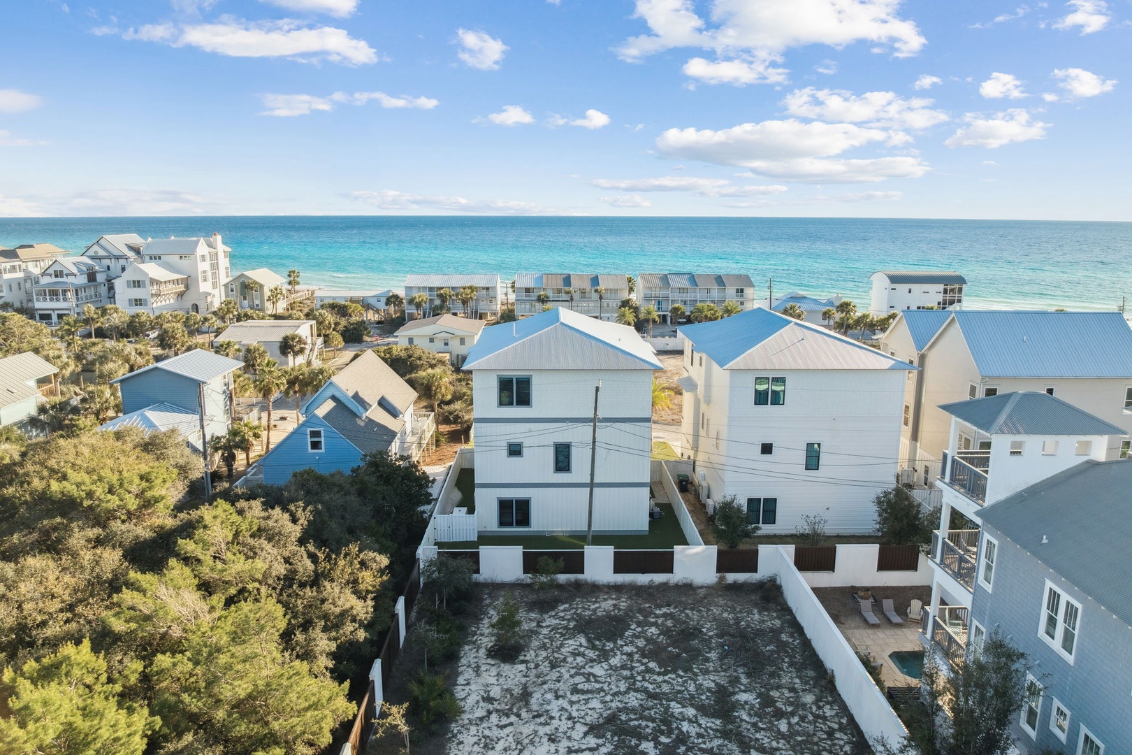 Coastal beach community featuring modern vacation homes with pristine white sand beaches and turquoise waters just steps away.
