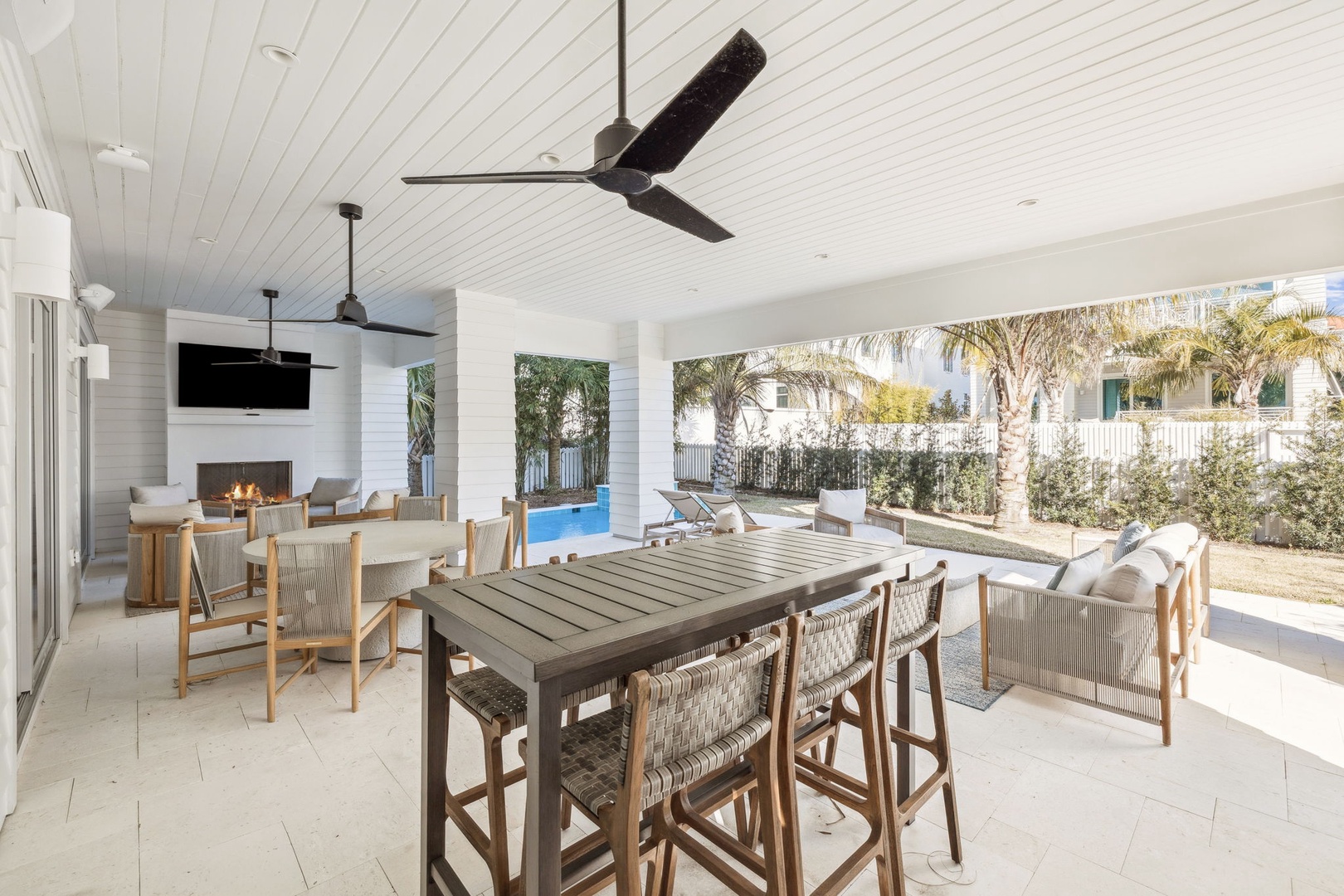 Your covered outdoor dining space features elegant seating, fireplace, and TV, opening to your private pool and garden oasis.