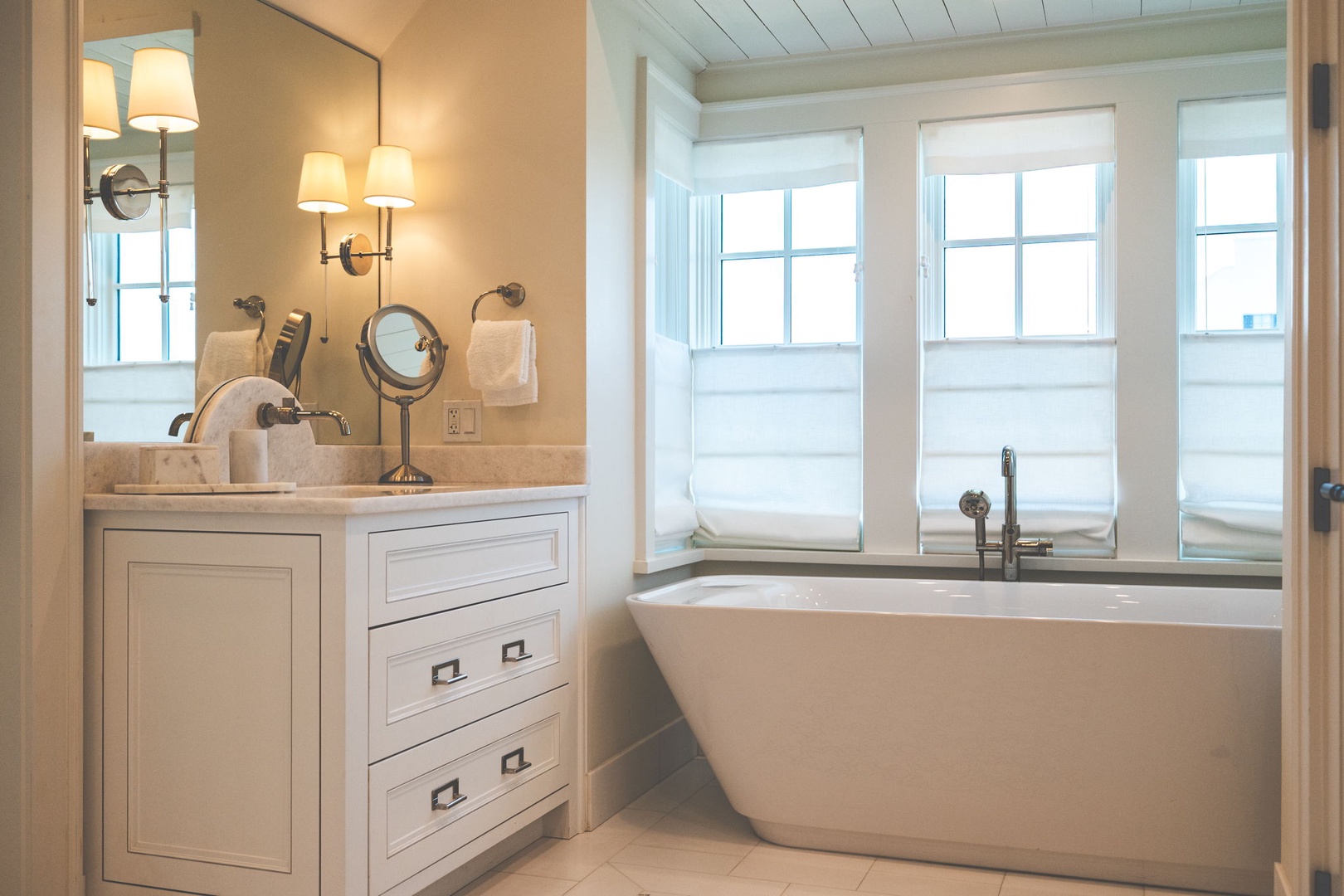 Unwind in your elegant bathroom featuring a luxurious soaking tub, elegant vanity with warm lighting, and soft natural light from tranquil windows.