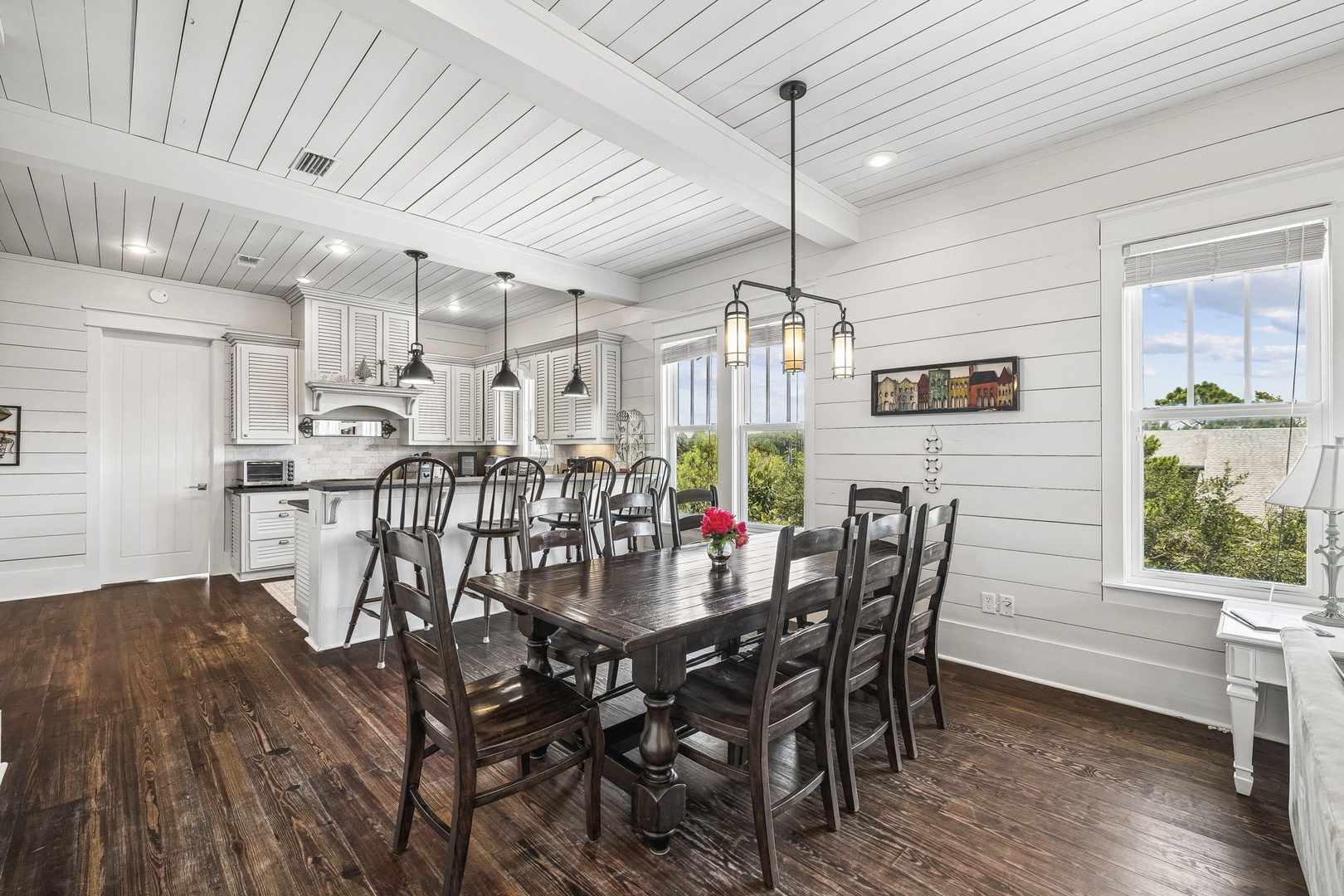 Gather around this spacious farmhouse dining table where your group can share meals and stories under warm pendant lighting. The bright open kitchen flows seamlessly into the dining area, making meal prep and conversation feel effortless.