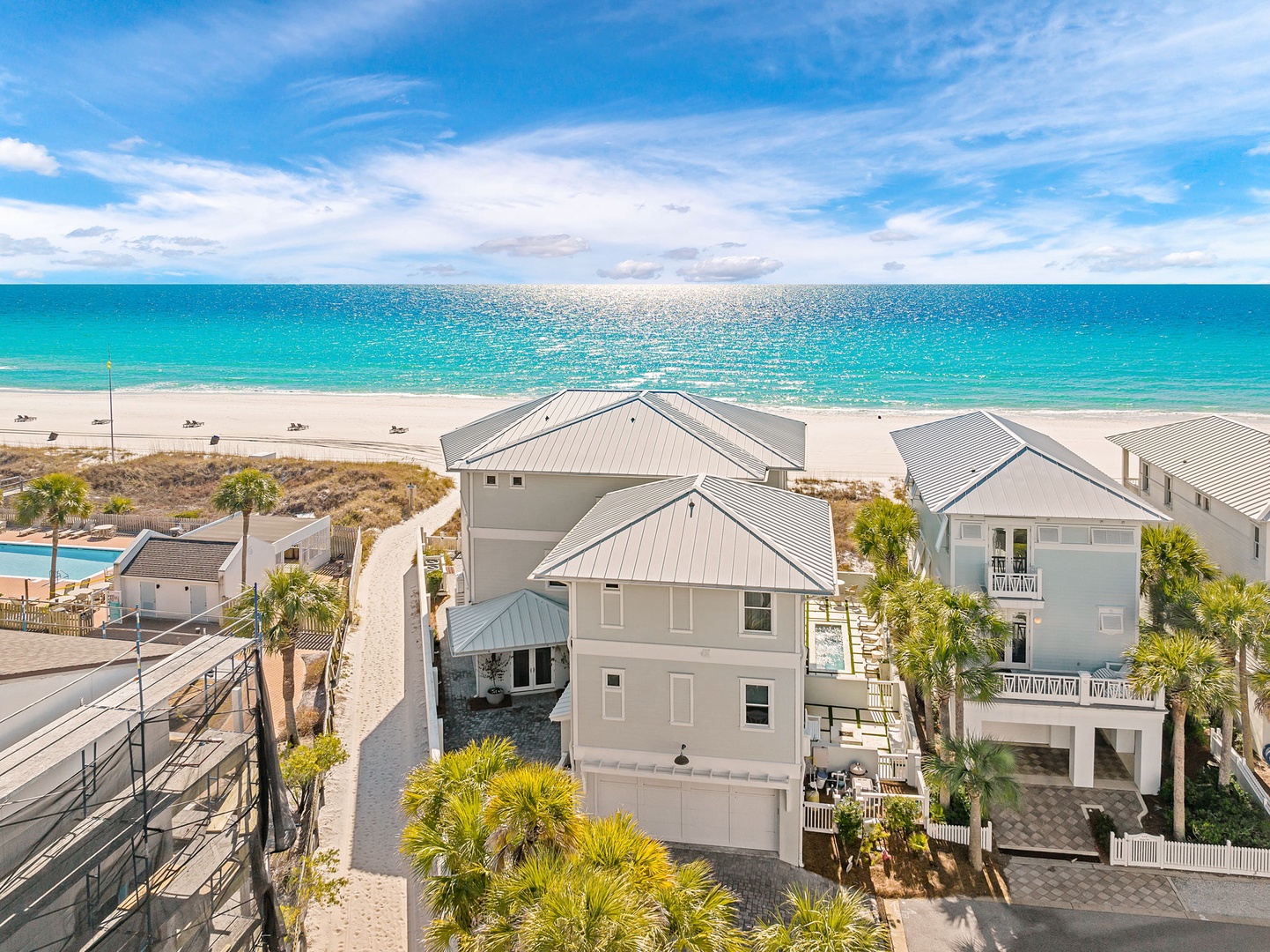 A beachfront neighborhood featuring modern coastal architecture, lush palms, and direct access to pristine turquoise waters and soft white sand.