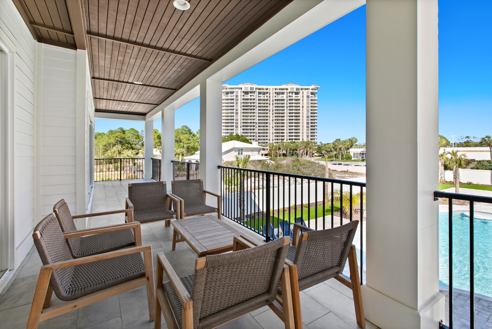 Step onto your private balcony and unwind in cozy seating as you take in views of lush greenery, the sparkling pool below, and coastal high-rises in the distance.