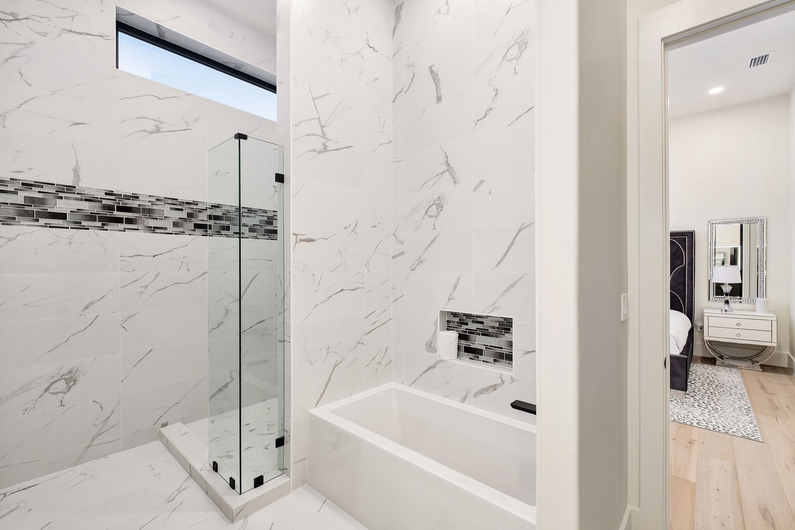 Luxurious marble bathroom with glass shower, soaking tub, and elegant mosaic accents for your ultimate relaxation.