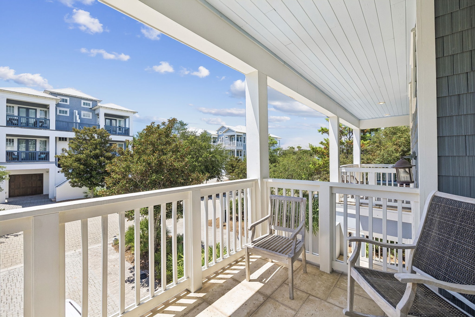 The covered balcony overlooks a peaceful coastal neighborhood, with nearby homes and greenery framing your private outdoor retreat. Perfect for morning coffee or watching the day unfold.