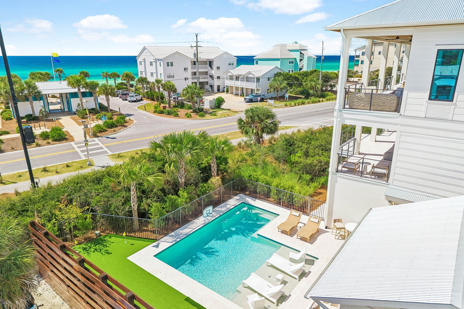 Coastal property featuring a private pool with lounge chairs, surrounded by tropical landscaping and neighboring beach houses, with the turquoise ocean waters visible in the distance.