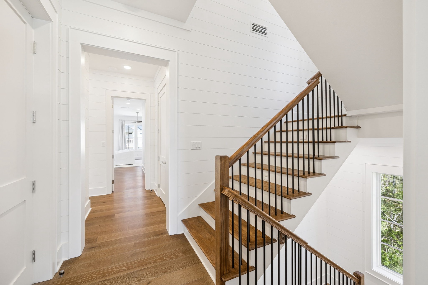 Step into this bright, welcoming entryway where warm wood floors and crisp white shiplap create the perfect coastal retreat atmosphere.